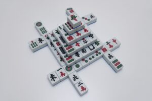 Vista cenital de fichas de Mahjong Solitario dispuestas en la clásica formación de caparazón de tortuga sobre un fondo blanco.