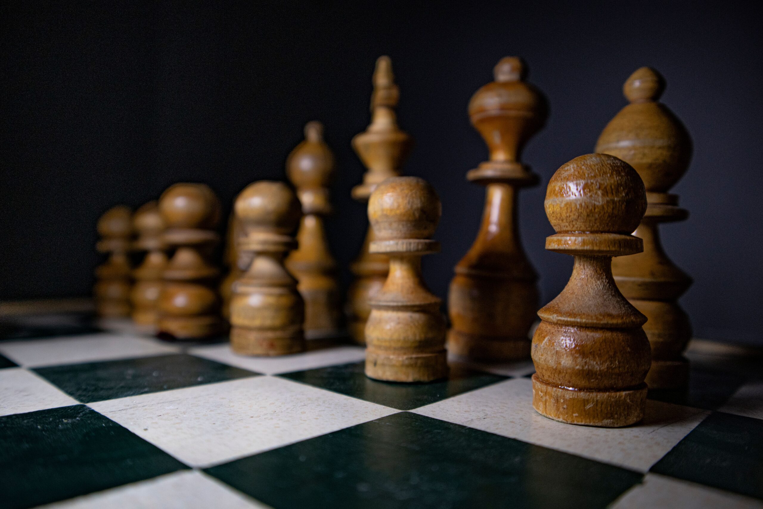 Piezas de ajedrez de madera dispuestas estratégicamente, simbolizando el análisis y el rigor profesional del juego. Piezas de ajedrez de madera dispuestas estratégicamente, simbolizando el análisis y el rigor profesional del juego.
