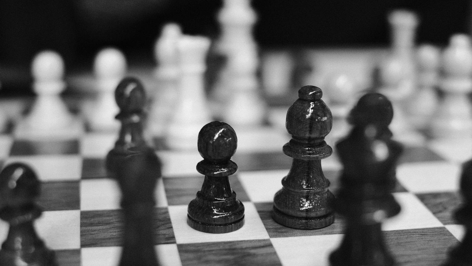 Detalle en blanco y negro de piezas negras sobre el tablero con enfoque nítido, resaltando la solidez posicional y la técnica del jugador moderno. Detalle en blanco y negro de piezas negras sobre el tablero con enfoque nítido, resaltando la solidez posicional y la técnica del jugador moderno.