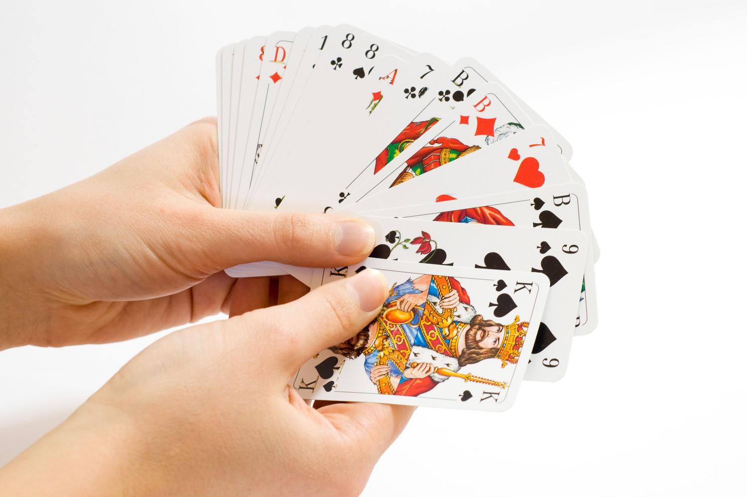 Abanico de cartas coloridas sostenidas en las manos sobre un fondo blanco, imagen limpia y genérica de un juego de cartas. Abanico de cartas coloridas sostenidas en las manos sobre un fondo blanco, imagen limpia y genérica de un juego de cartas.