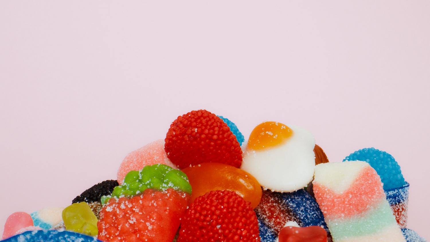 Surtido de gomitas azucaradas sobre un fondo rosa pastel, capturando la estética dulce y colorida del juego. Surtido de gomitas azucaradas sobre un fondo rosa pastel, capturando la estética dulce y colorida del juego.