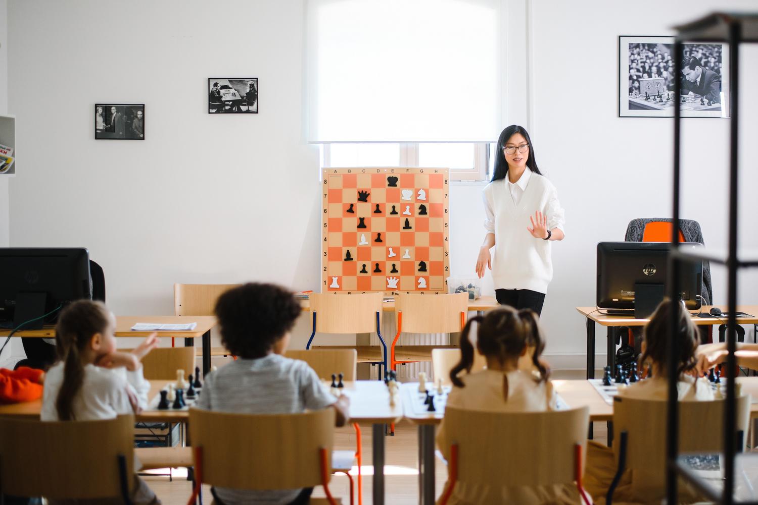 Profesora de ajedrez en clase Profesora de ajedrez impartiendo una lección didáctica a sus alumnos en el colegio.