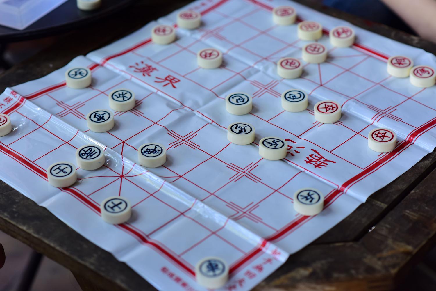 Vista atmosférica de un tablero de Xiangqi con piezas en juego sobre una mesa de madera. Vista atmosférica de un tablero de Xiangqi con piezas en juego sobre una mesa de madera.