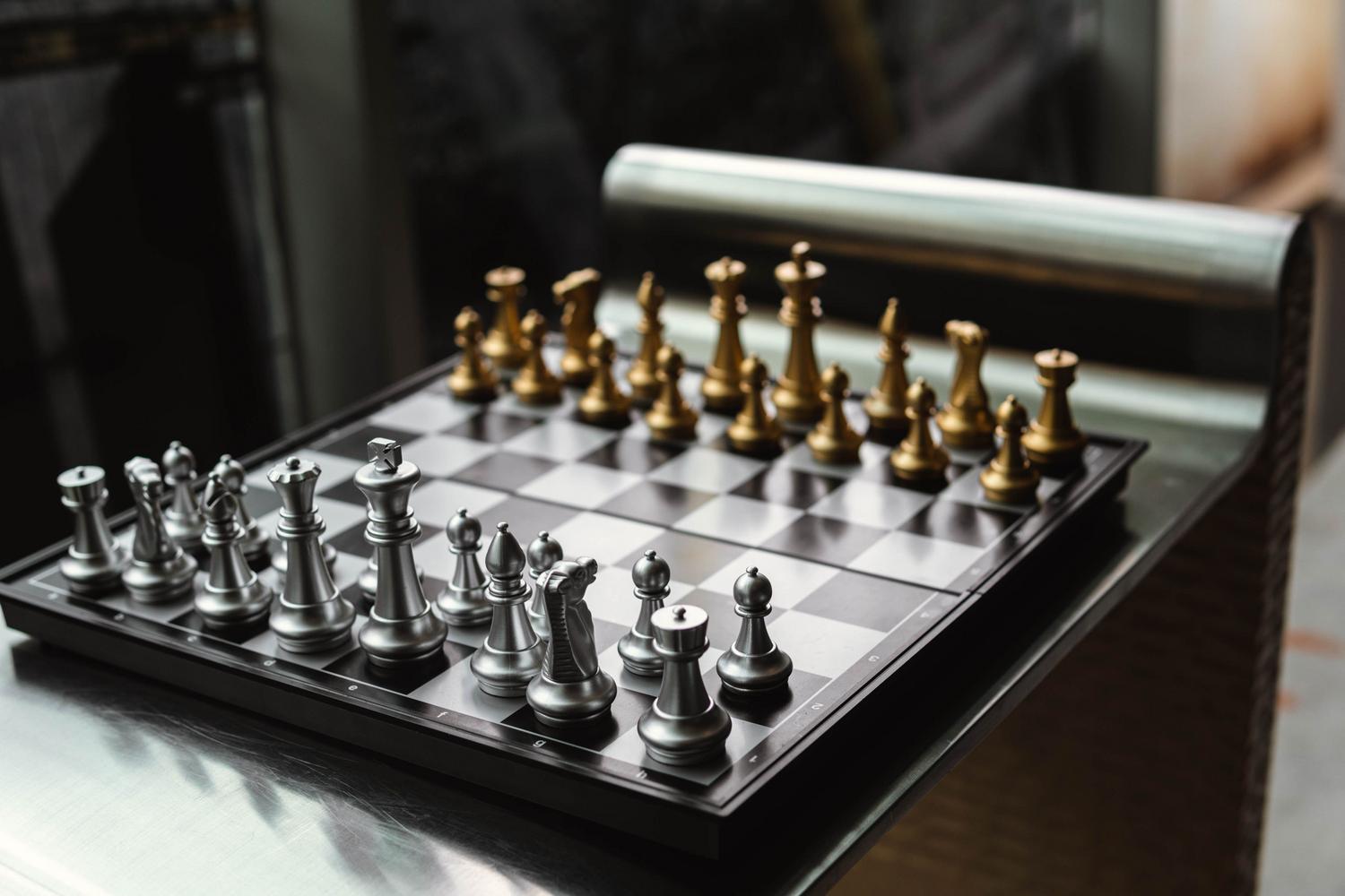 Juego de ajedrez moderno de oro y plata sobre una superficie reflectante, representando la elegancia contemporánea y el valor como objeto de decoración. Juego de ajedrez moderno de oro y plata sobre una superficie reflectante, representando la elegancia contemporánea y el valor como objeto de decoración.