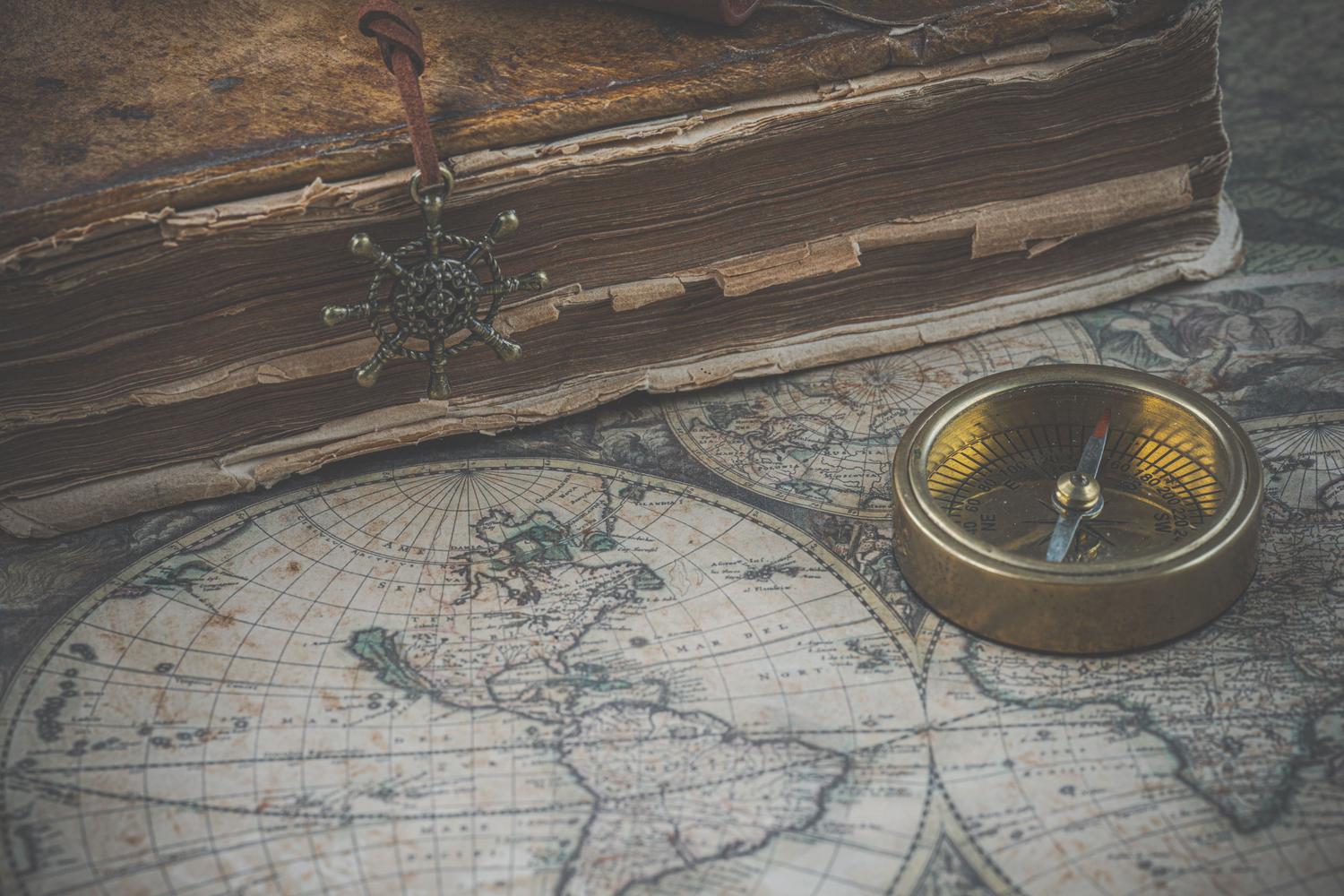 Mapa antiguo, brújula y libro clásico, evocando las sagas de fantasía y la búsqueda de caminos épicos. Mapa antiguo, brújula y libro clásico, evocando las sagas de fantasía y la búsqueda de caminos épicos.