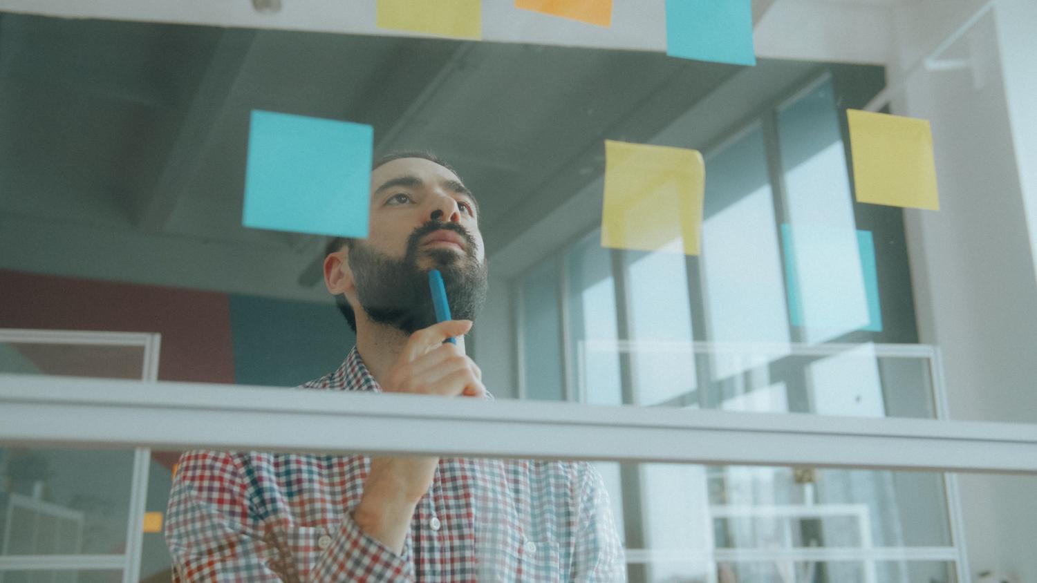Hombre analizando información y organizando ideas con notas adhesivas en una oficina, ejemplo de pensamiento crítico aplicado al mundo real. Hombre analizando información y organizando ideas con notas adhesivas en una oficina, ejemplo de pensamiento crítico aplicado al mundo real.